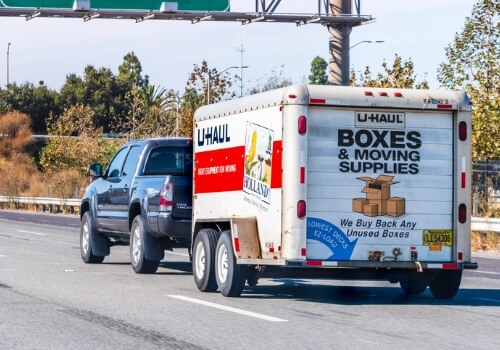 A truck pulls a U-Haul down the highway, which is one of the services you can find at Curt's Transportation Service, in addition to finding "Cabs Near Me"