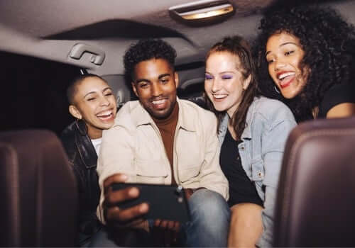 Four friends smile for a selfie in the back of a cab after they called Curt's Transportation Services, a Taxi Company in East Peoria IL