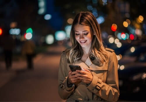 A woman smiles while searching her phone for Taxi Cabs in East Peoria IL