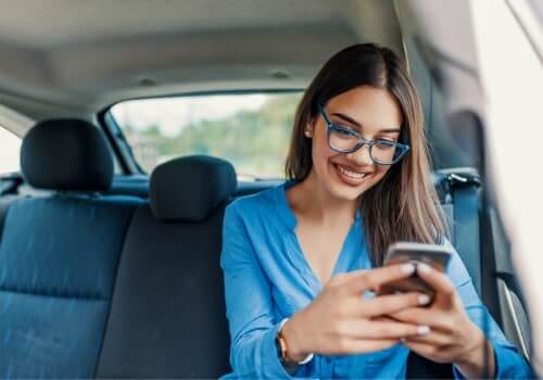 A woman smiles at her phone after getting Taxi Service in Pekin IL