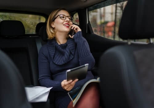 A business woman laughs while talking on the phone in the backseat of a taxi after calling Curt's Transportation Services, which serves as an Airport Taxi in Morton IL.