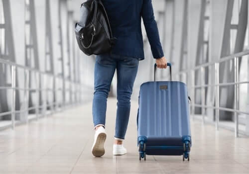 A man pulls his luggage behind him as he prepares to leave the airport. If you're asking "How Do I Get Home from Peoria International Airport" call Curt's Transportation Services.