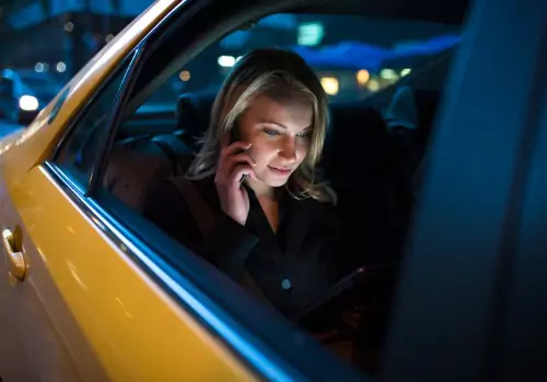 A woman talks on the phone while riding in the back of a cab. Does Tazewell County Have a Taxi Service? The answer is Curt's Transportation Services.