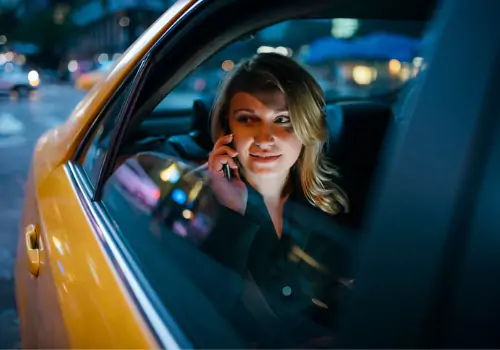 A woman listens to a voice mail while in the back of a cab from Curt's Transportation Services, which offers Local Taxi Service in Pekin IL