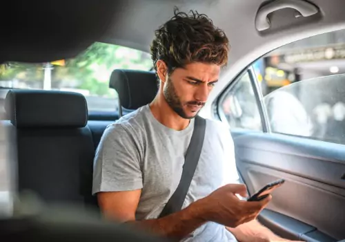 A man looks at his phone while riding in a cab from Curt's Transportation Services, which offers Taxi Service in Peoria County IL