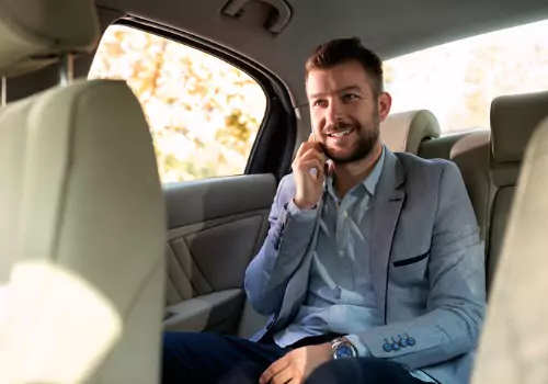 A man smiles while talking on the phone in the back of his cab from Curt's Transportation Services, which are Local Taxis in Tazewell County IL